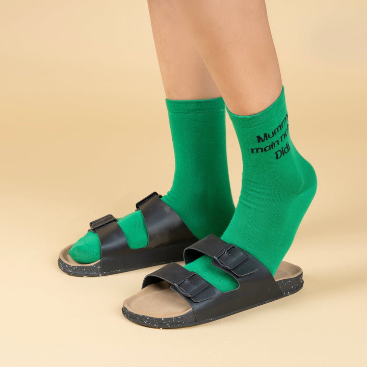 Green socks with text worn with black sandals on a beige background