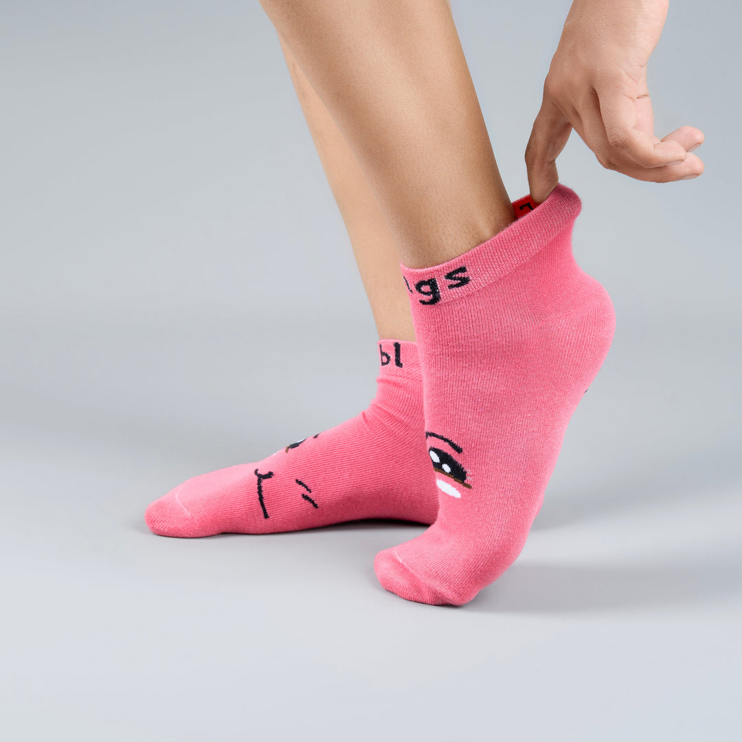 Person wearing pink socks with cartoon designs on a gray background