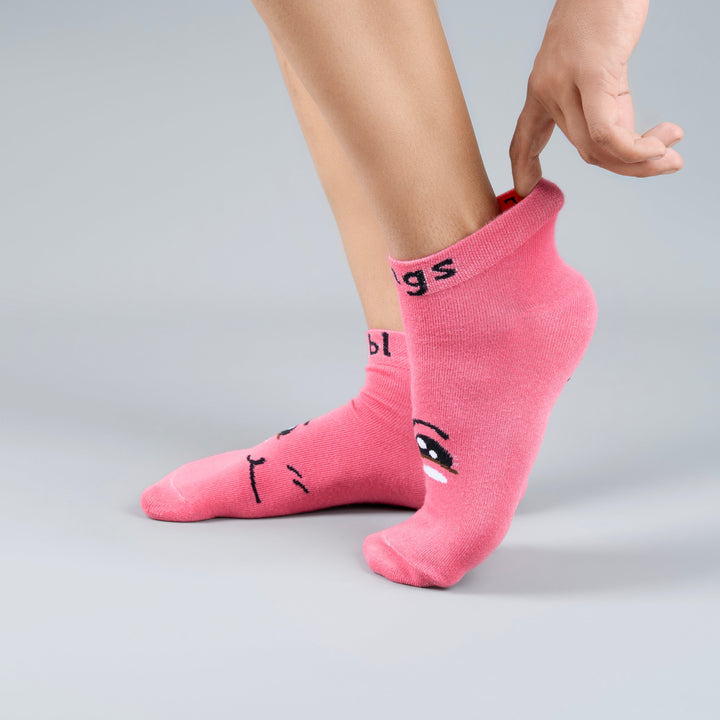 Person wearing pink socks with cartoon designs on a gray background