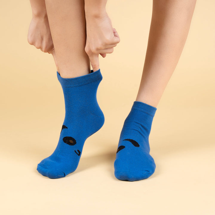 Blue socks with black paw prints worn by a person on a beige background