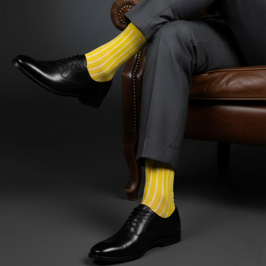 Person wearing a gray suit with yellow striped socks sitting on a brown leather chair.