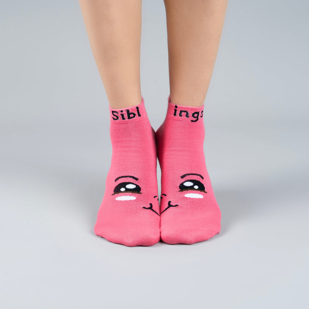 Pink socks with cartoon face design and text on a gray background-Siblings Forever Edition- Fun Expression-